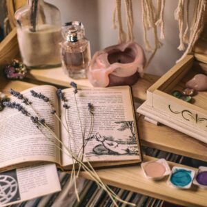 Aesthetic setup with books, lavender, crystals, and candles on a wooden shelf.